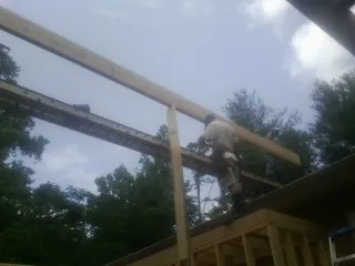 Carpenter setting a ridge beam over a new addition frame — Ice Dam Removal by Roofing Brothers in Lascassas