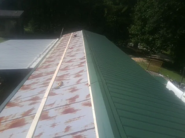 Old rusted panels beside newly installed green metal roofing — Wind Damage Roof Repair by Roofing Brothers in Lascassas