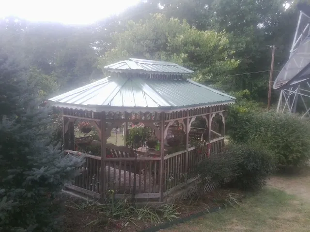 Green metal roof on a backyard gazebo surrounded by garden beds in Lascassas
