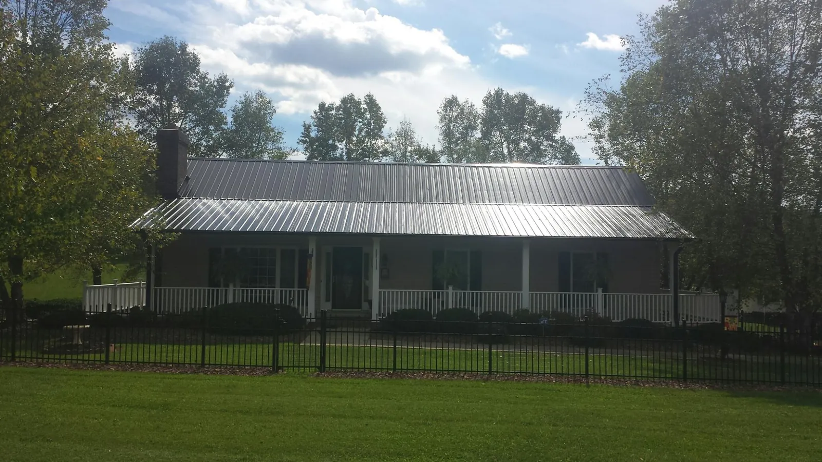 Gray metal roof on a brick ranch with a full width front porch — Gutter Guard Installation work by our crew in Lascassas