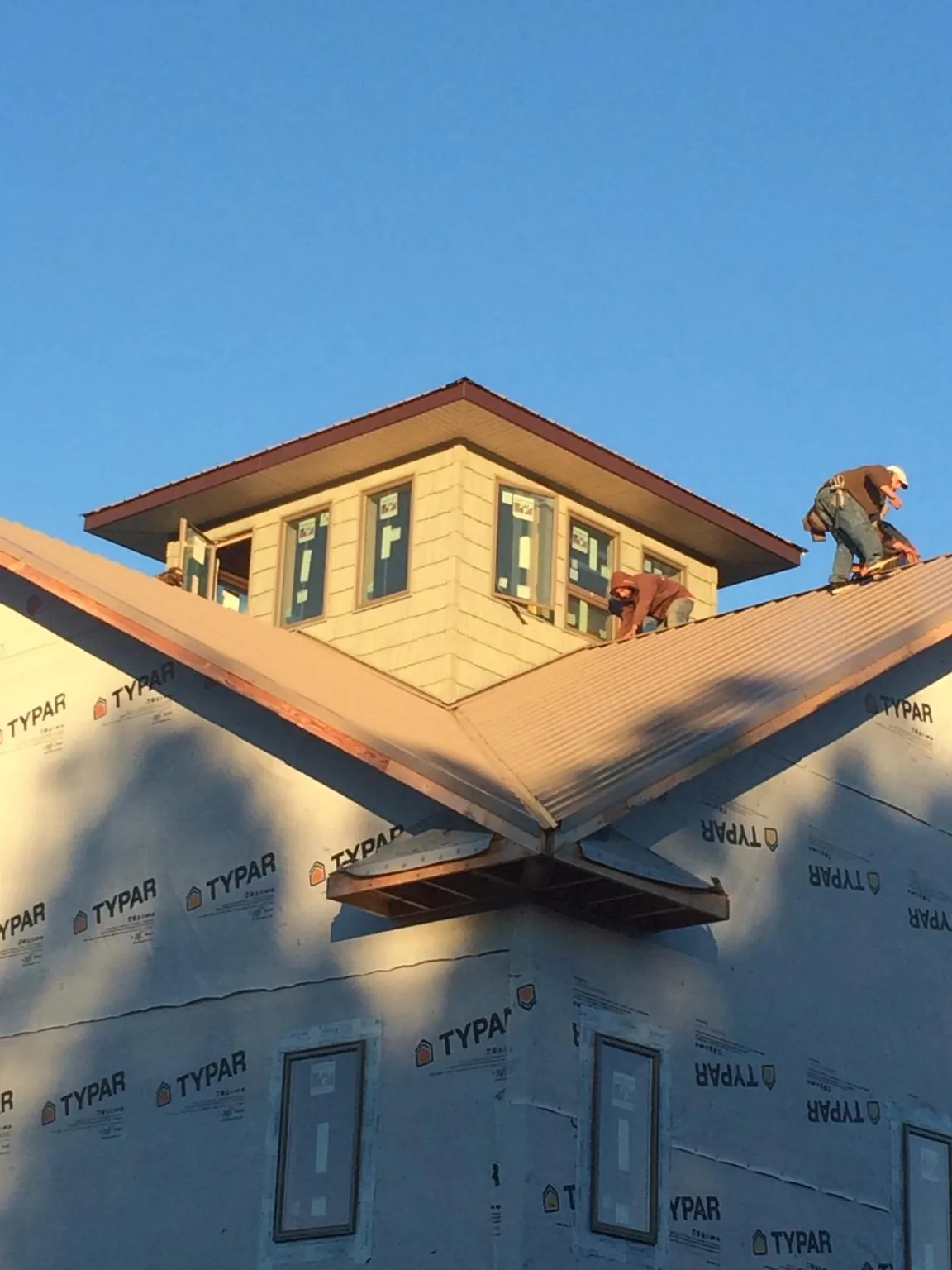 Roofers working around a rooftop cupola on a new metal roof at sunset — Roof Waterproofing in Lascassas by Roofing Brothers